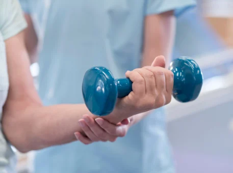Physiotherapist holding a dumbbell during a rehabilitation session