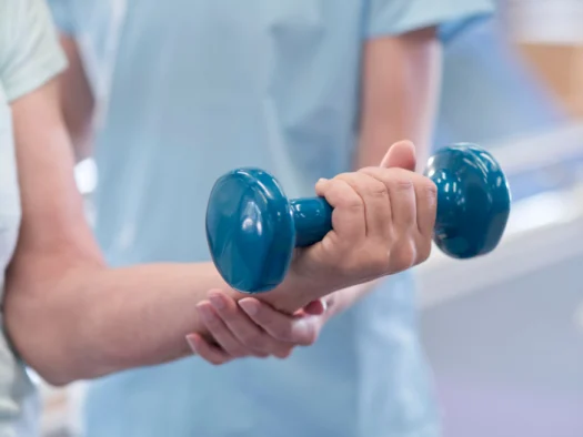 Physiotherapist holding a dumbbell during a rehabilitation session